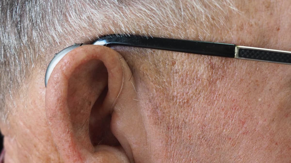 Hoorhulpmiddelen en telefoon naast notitieboek op tafel
