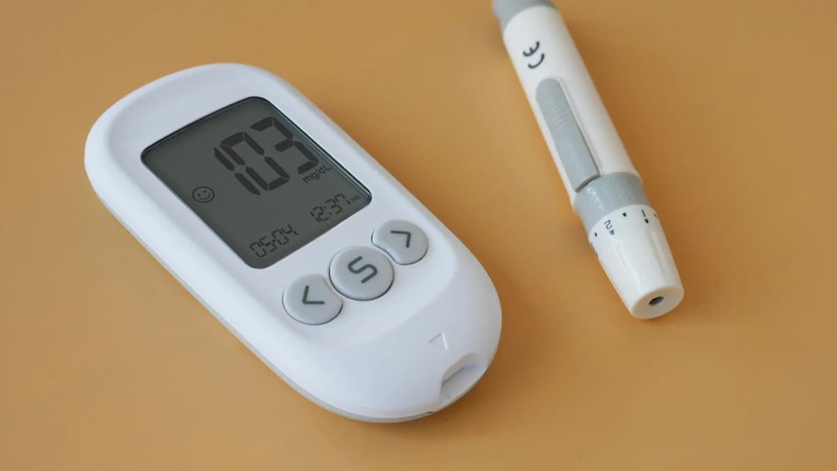 Diabetes hulpmiddelen zoals glucosemeter, sensor en pomp op tafel bij zorggesprek