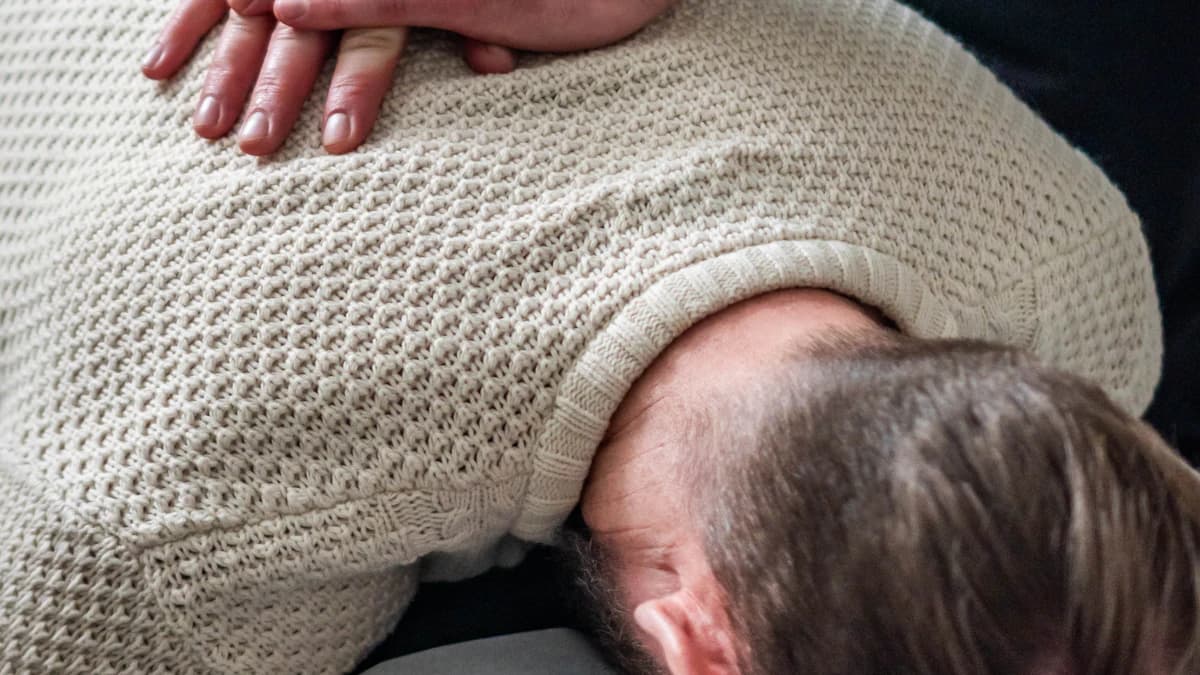 Oudere oefent opstaan en balans met begeleiding van geriatriefysiotherapeut